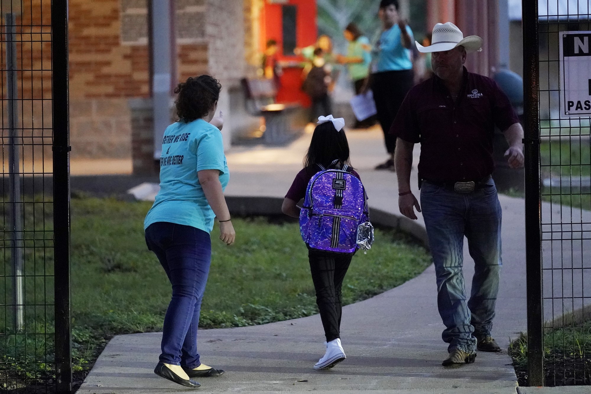 A lady points into the distance for a young girl to show her where to go.