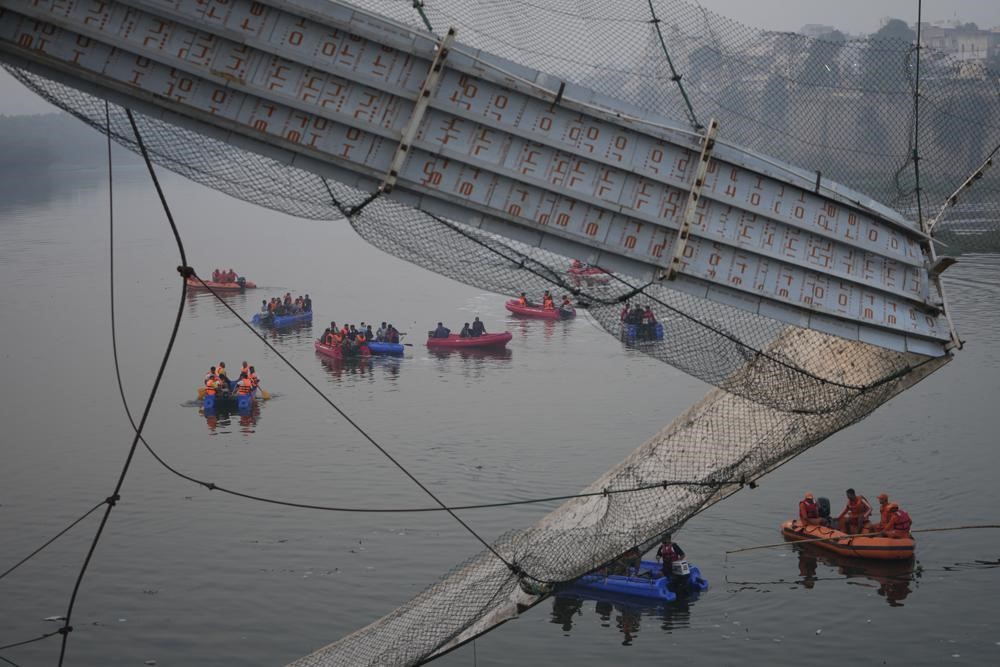 Rescuers on boats in India after a bridge collapsed