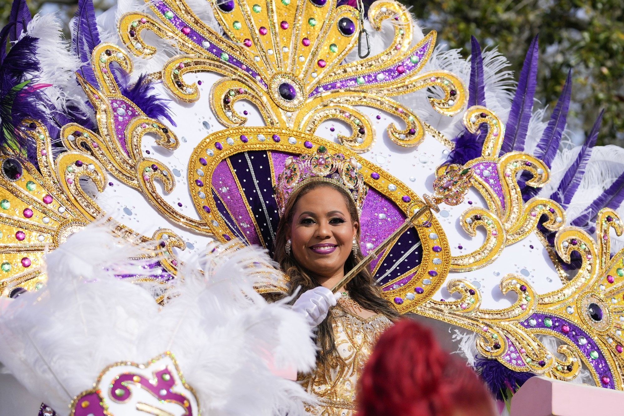 A woman in an elaborate gold costume that fans out behind her like a peacock tail. 