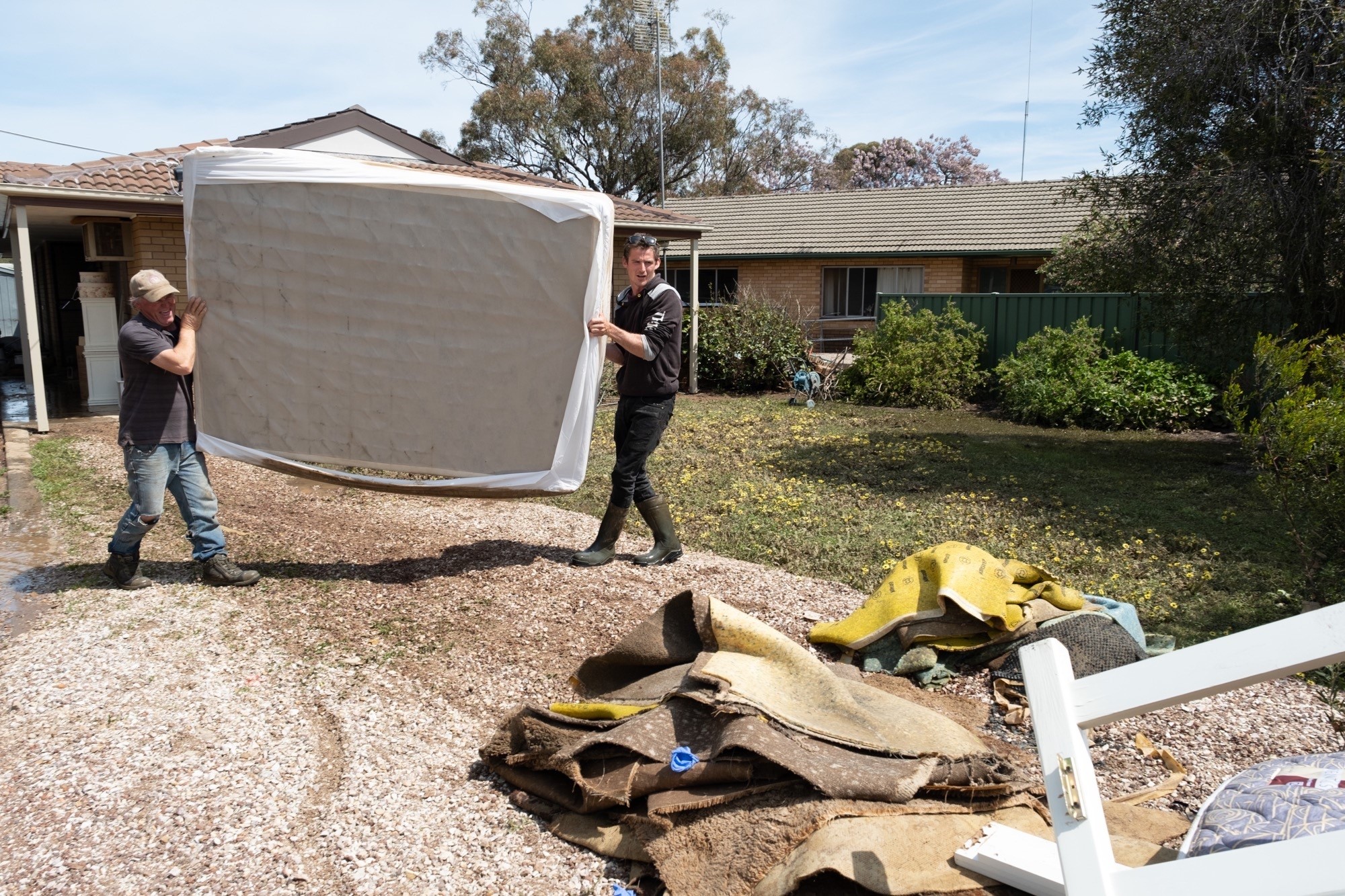 Men carry out a mattress from a flooded home.