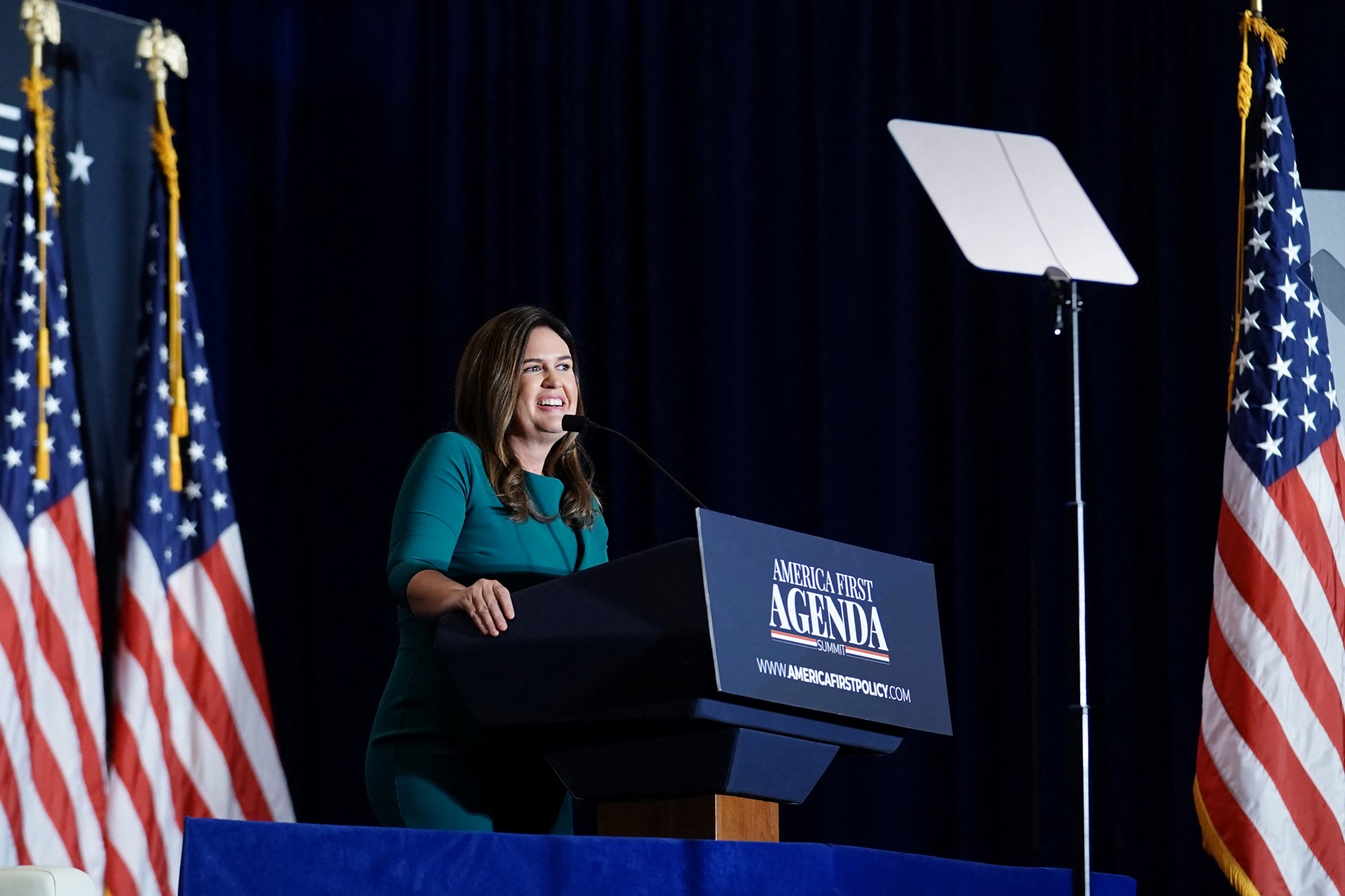 Sarah Huckabee stands at a podium and smiles