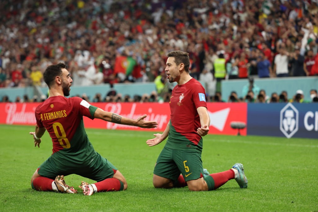 Bruno Fernandes and Raphael Guerreiro slide on their knees to celebrate a Qatar World Cup goal against Switzerland.