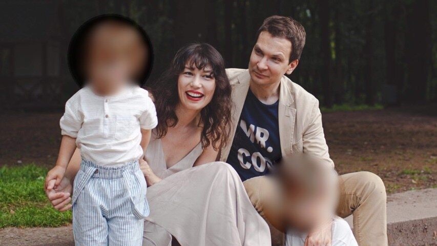 A mother and father with their two children, whose faces are blurred for privacy.