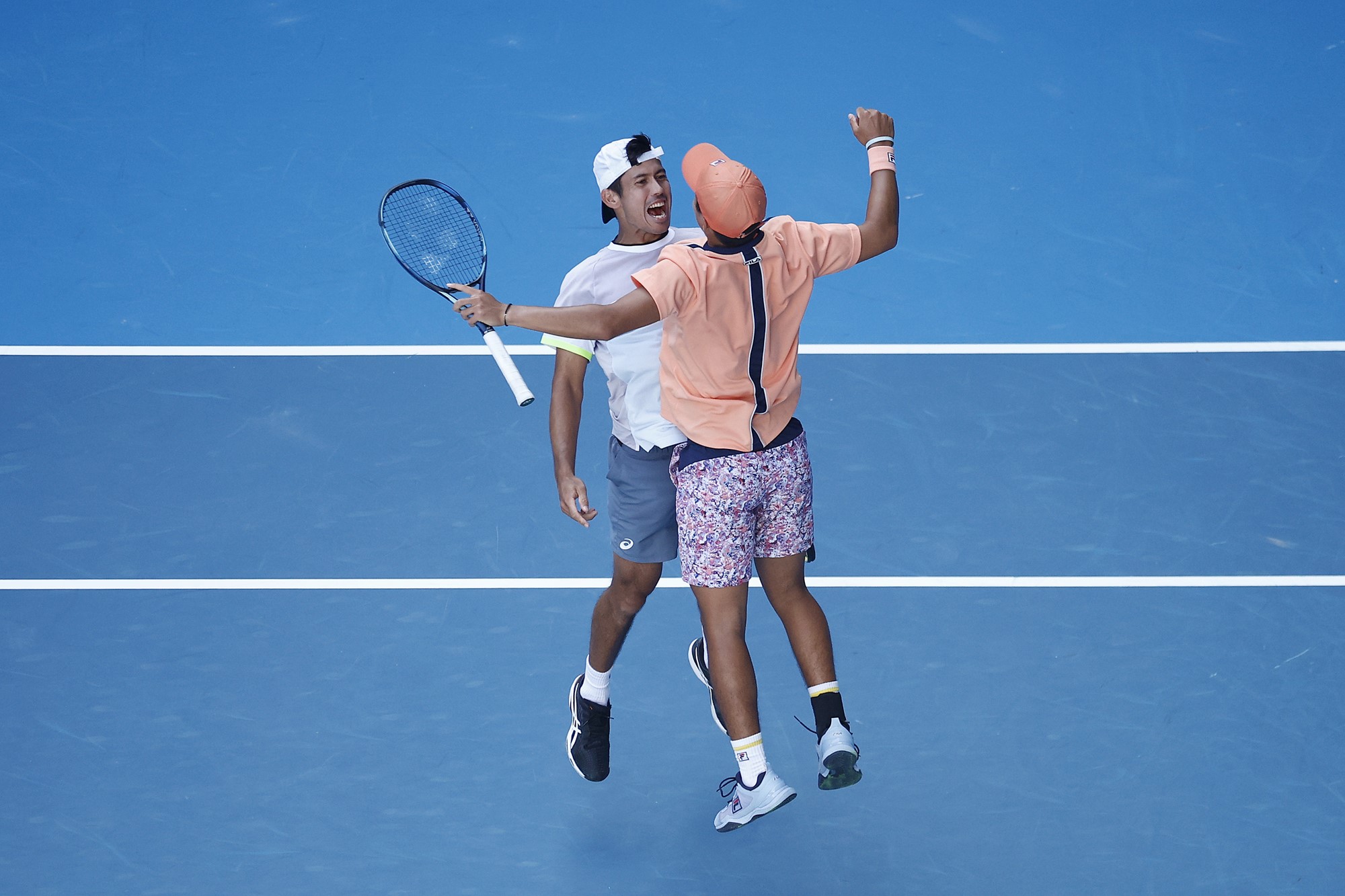Two tennis players chest bump.