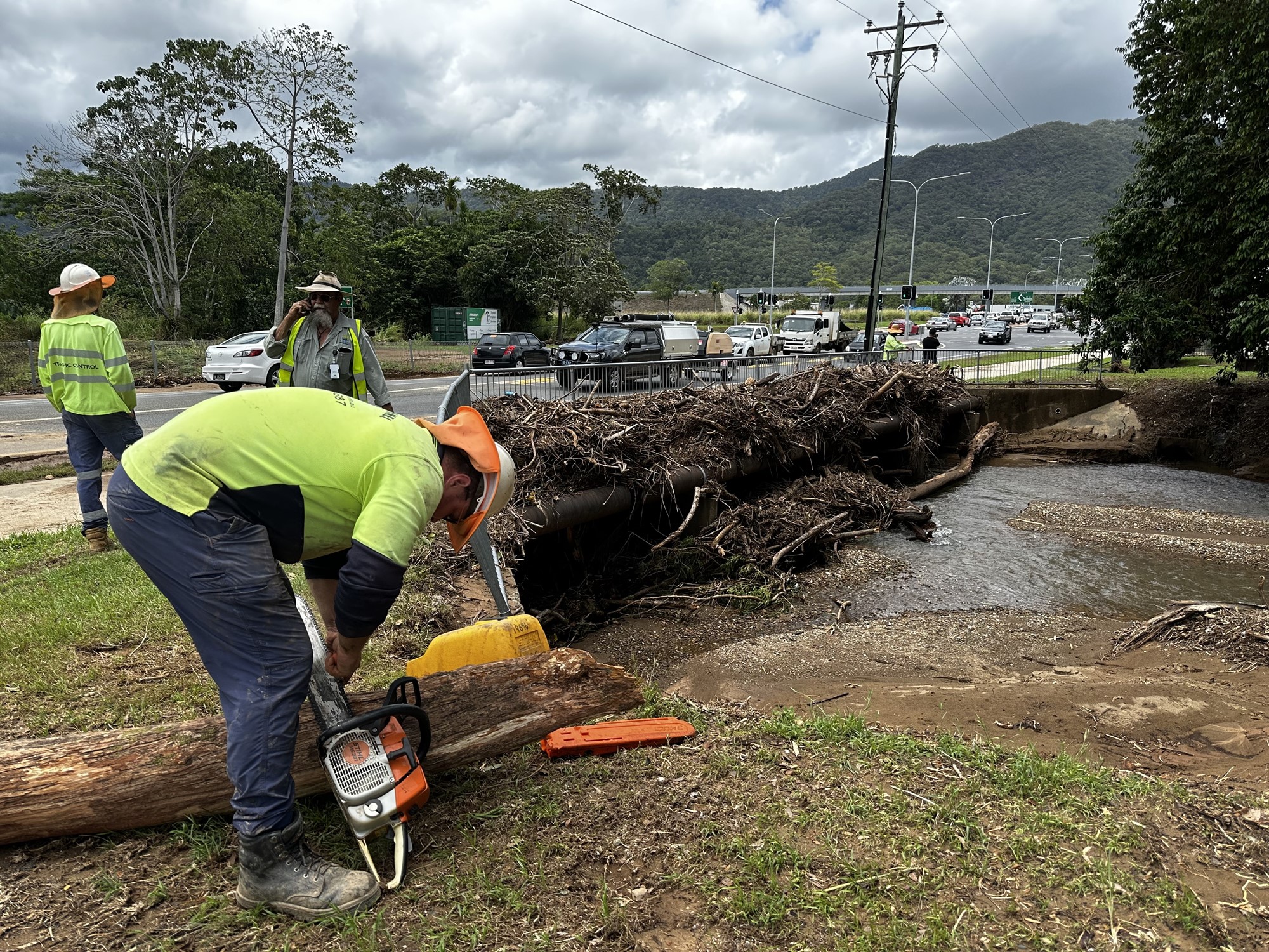 council workers use chainsaws to break up branches blocking a drain