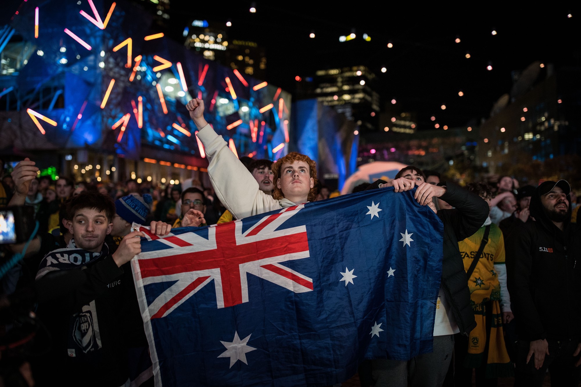 A young man holds up an Australian flag.