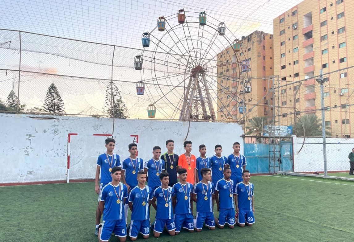 Boys wearing sports uniform taking a photo on a football field with a ferris wheel in the distance