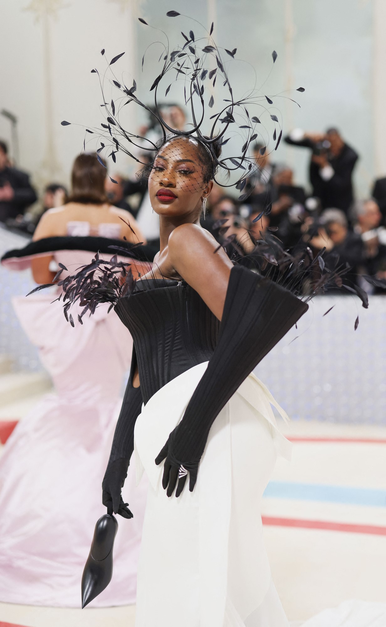 Tems wears a black and white gown with an elaborate feather headpiece.