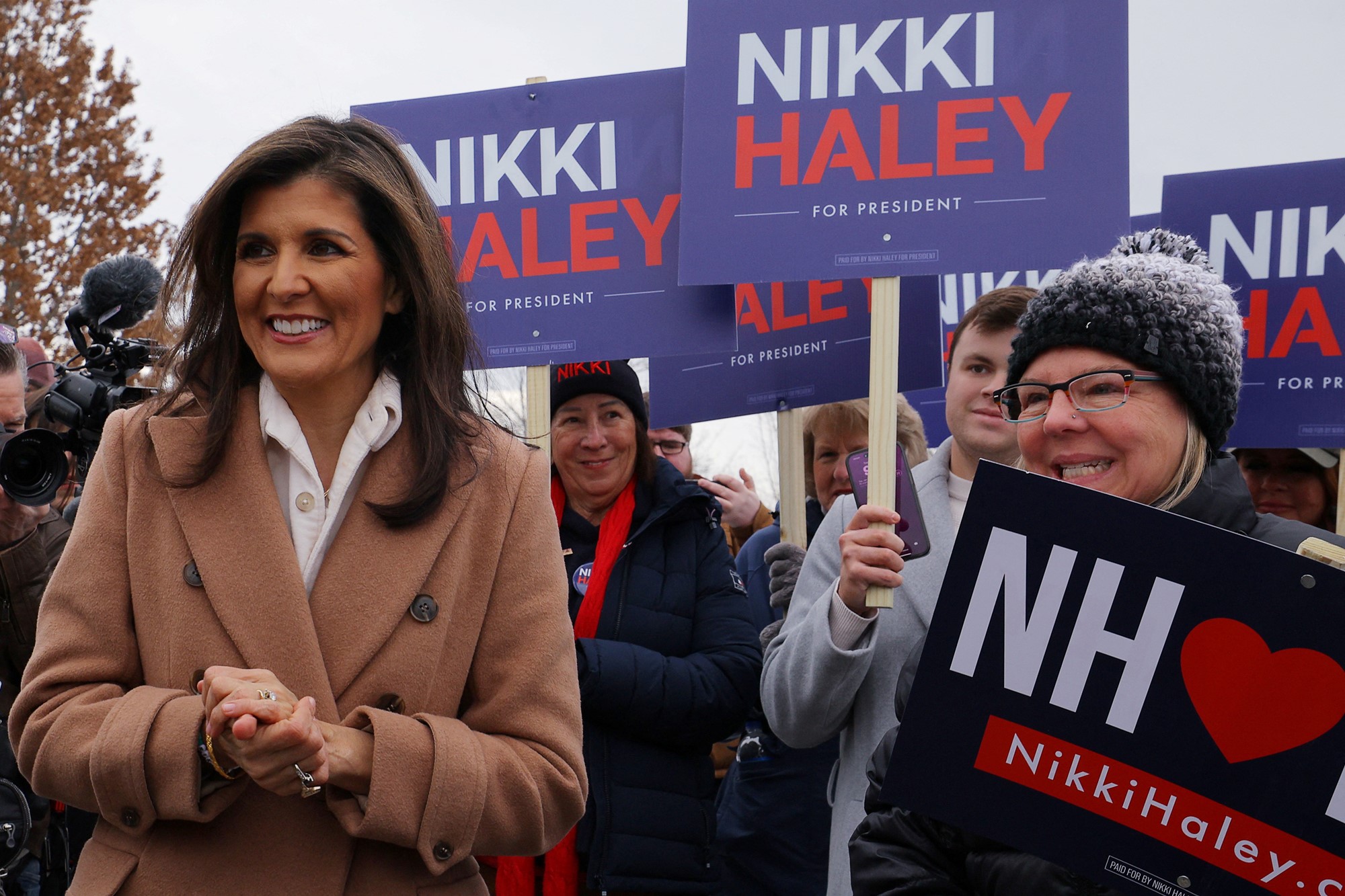 Nikki Haley stands in front of people with signs reading 'Nikki Haley for president.'