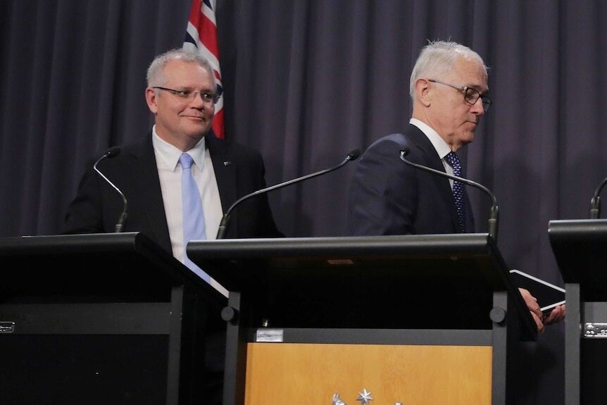 Morrison looks at Turnbull, who is walking away from a podium after his final press conference.