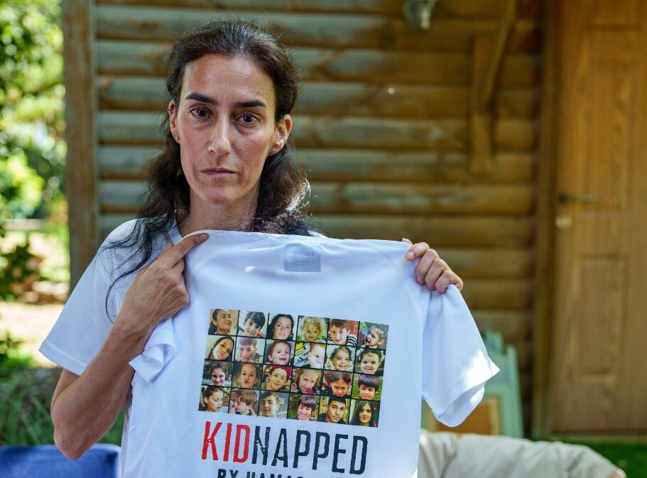 A woman holding a shirt with pictures of small children on it with the word "kidnapped" on it