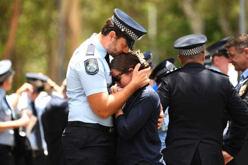 Two police officers hug and cry together.