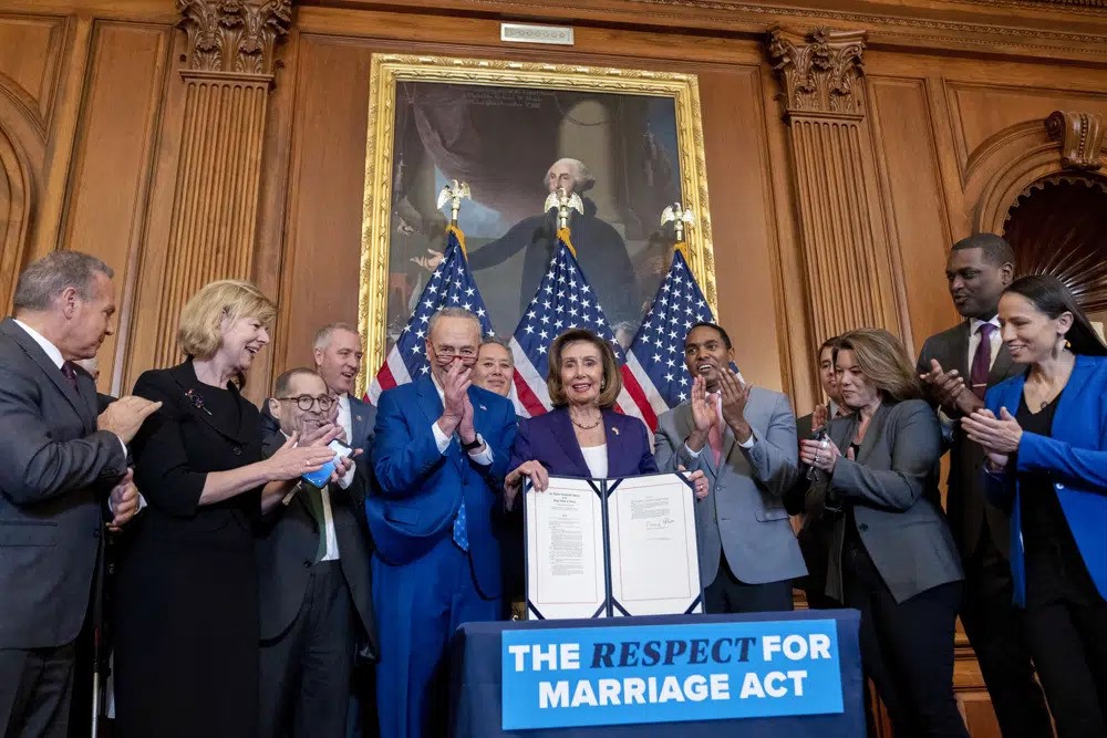 House Speaker Nancy Pelosi of Calif., accompanied by Senate Majority Leader Sen. Chuck Schumer of N.Y., center left, and other members of congress, signs the H.R. 8404, the Respect For Marriage Act, on Capitol Hill in Washington, Thursday, Dec. 8, 2022.