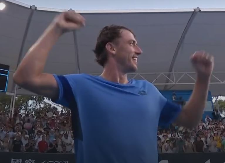 A tennis player celebrates with his arms in the air.