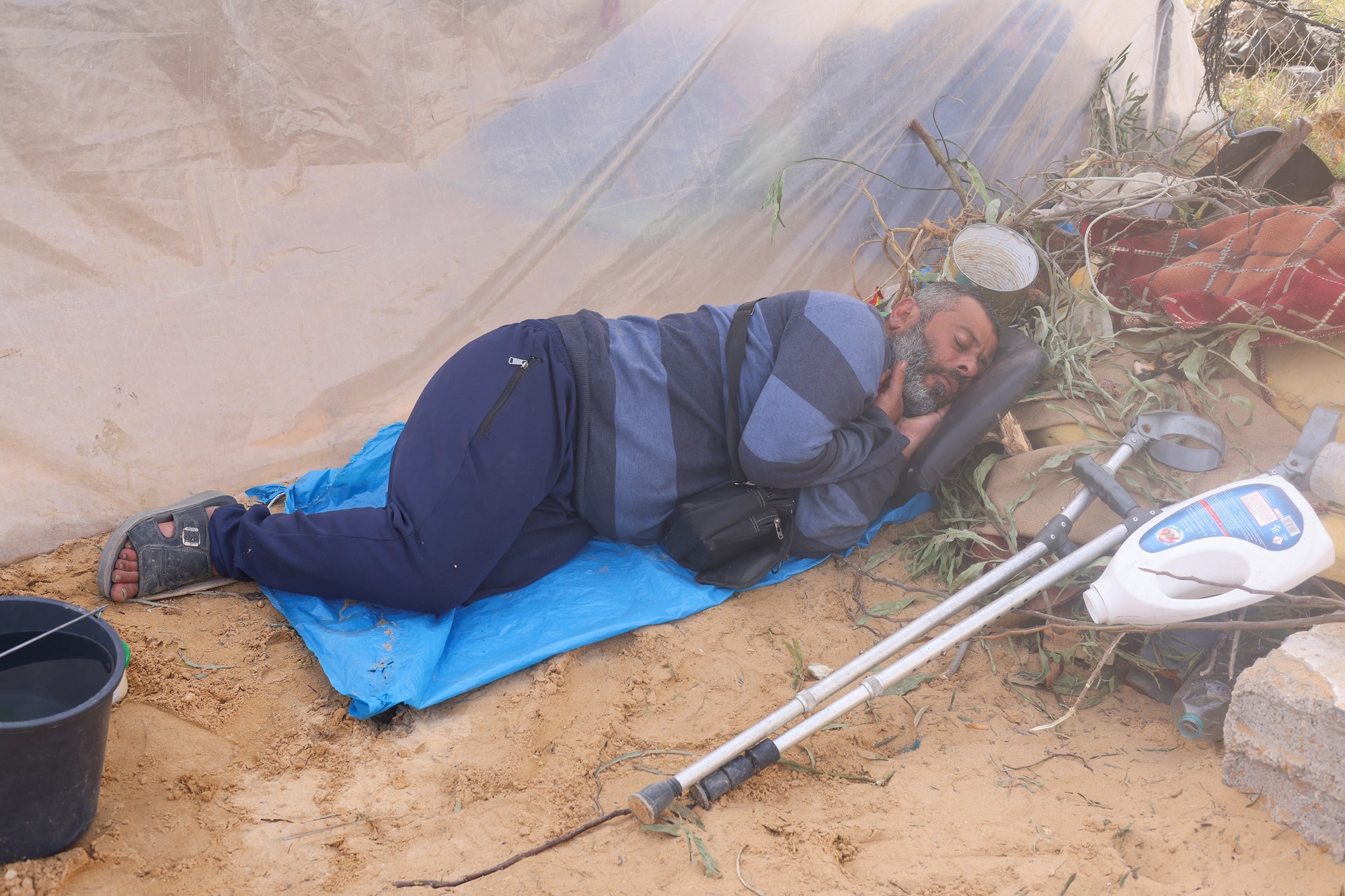 Man sleep on the ground covered by blue tarp