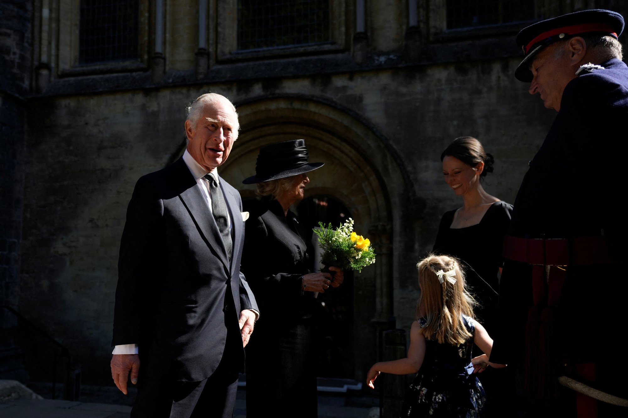 Charles and Camilla receive yellow flowers for a little girl.