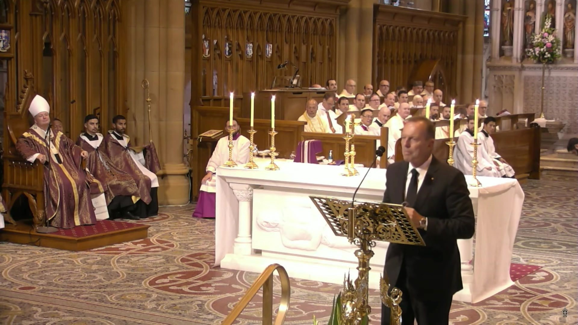 Tony Abbott stands at the front of a church at a  lecturn