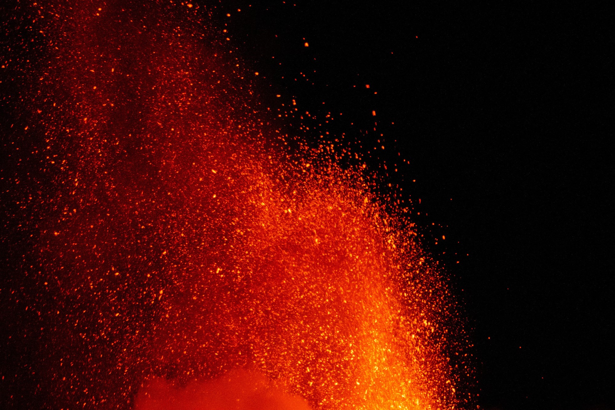 Red light spews from a volcano. 