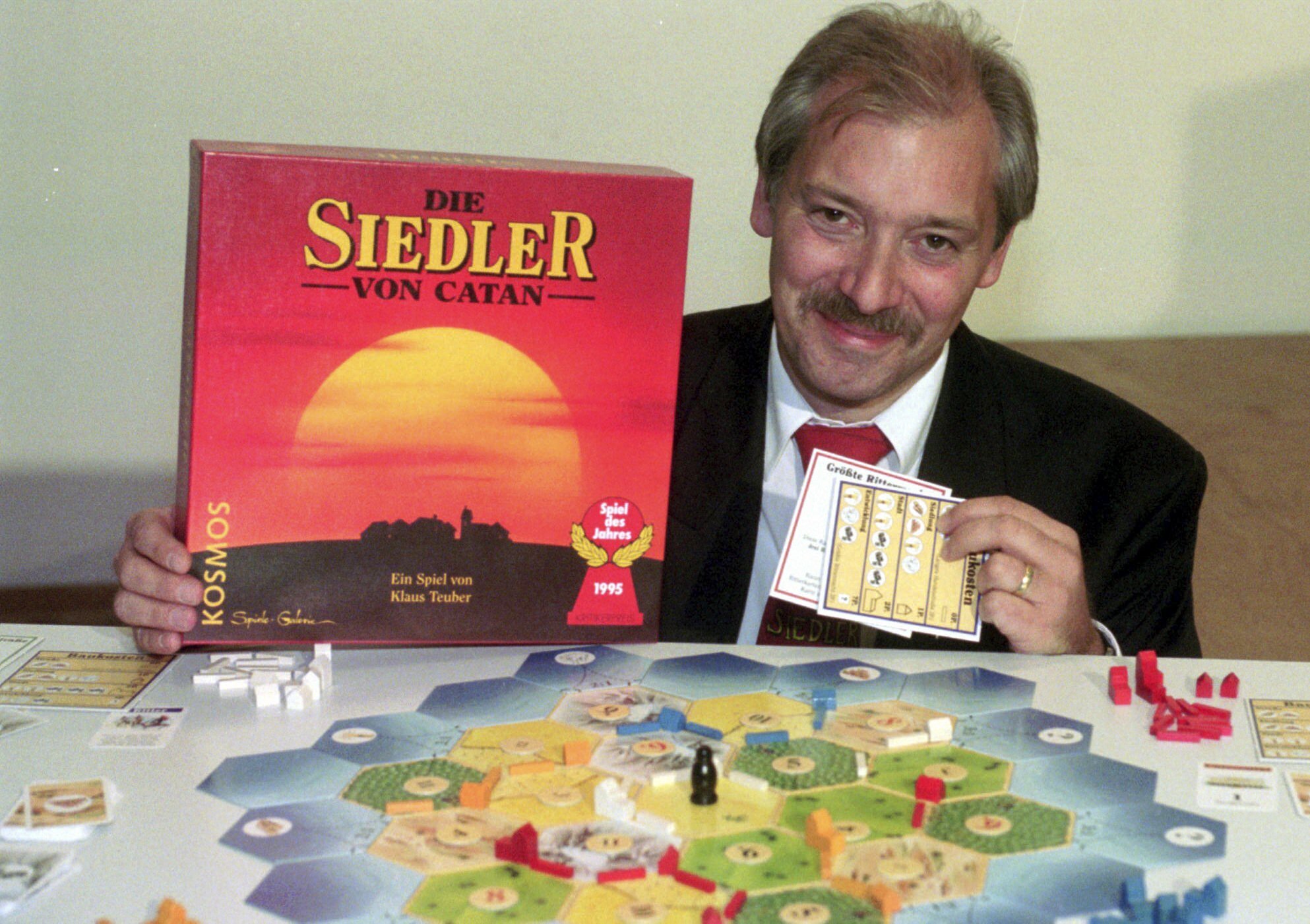 Klaus Teuber posts with a box of the Settlers of Catan board game. 