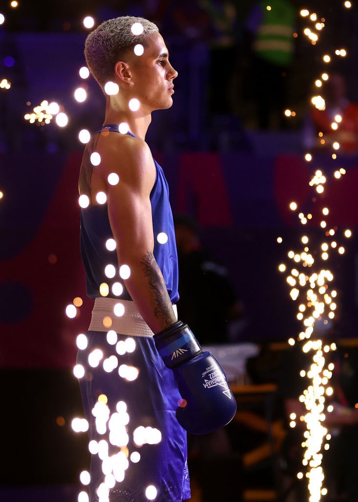 a boxer stands preparing to enter the ring with pyrotechnics going off around him