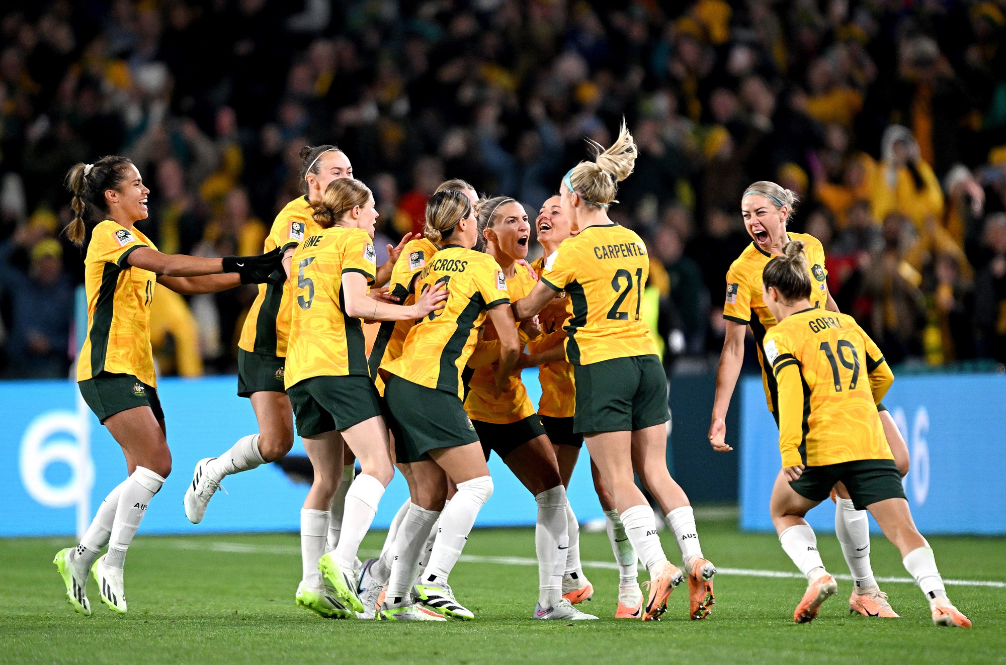The Matildas run together to celebrate on the field.
