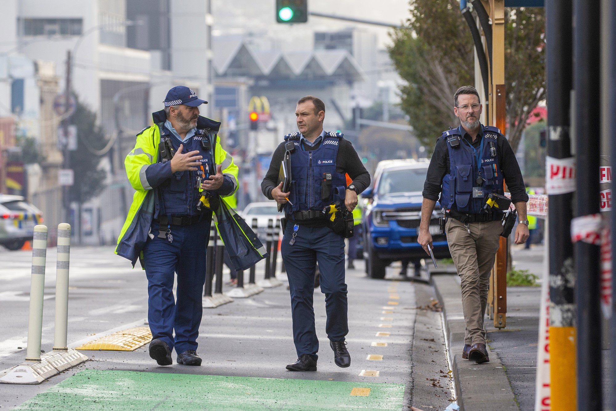 Three police men walk down the street.