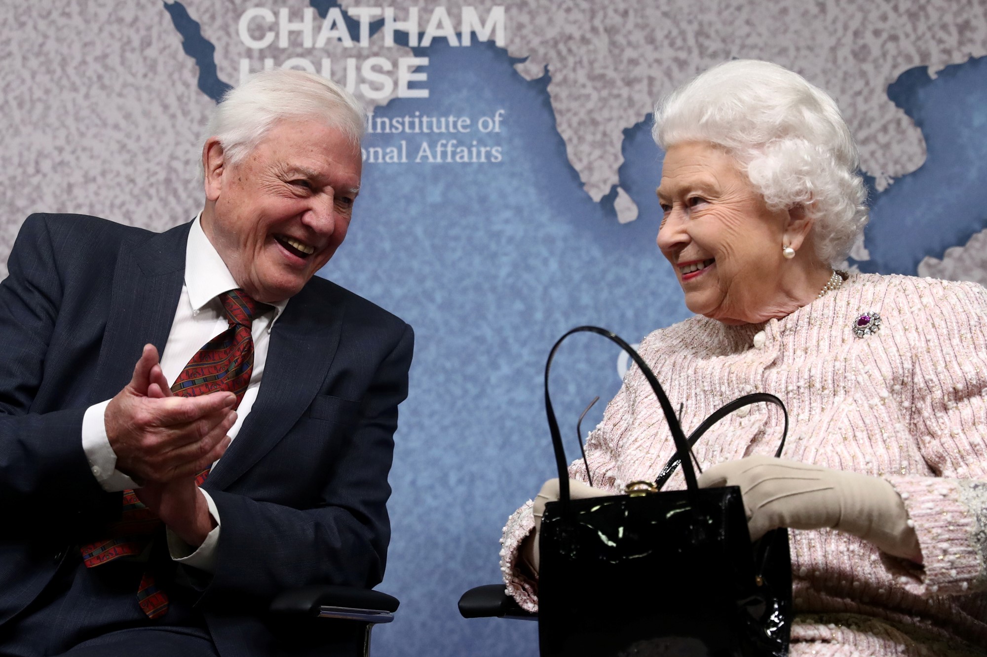 Sir David Attenborough turns towards Queen Elizabeth II at Chatham House.