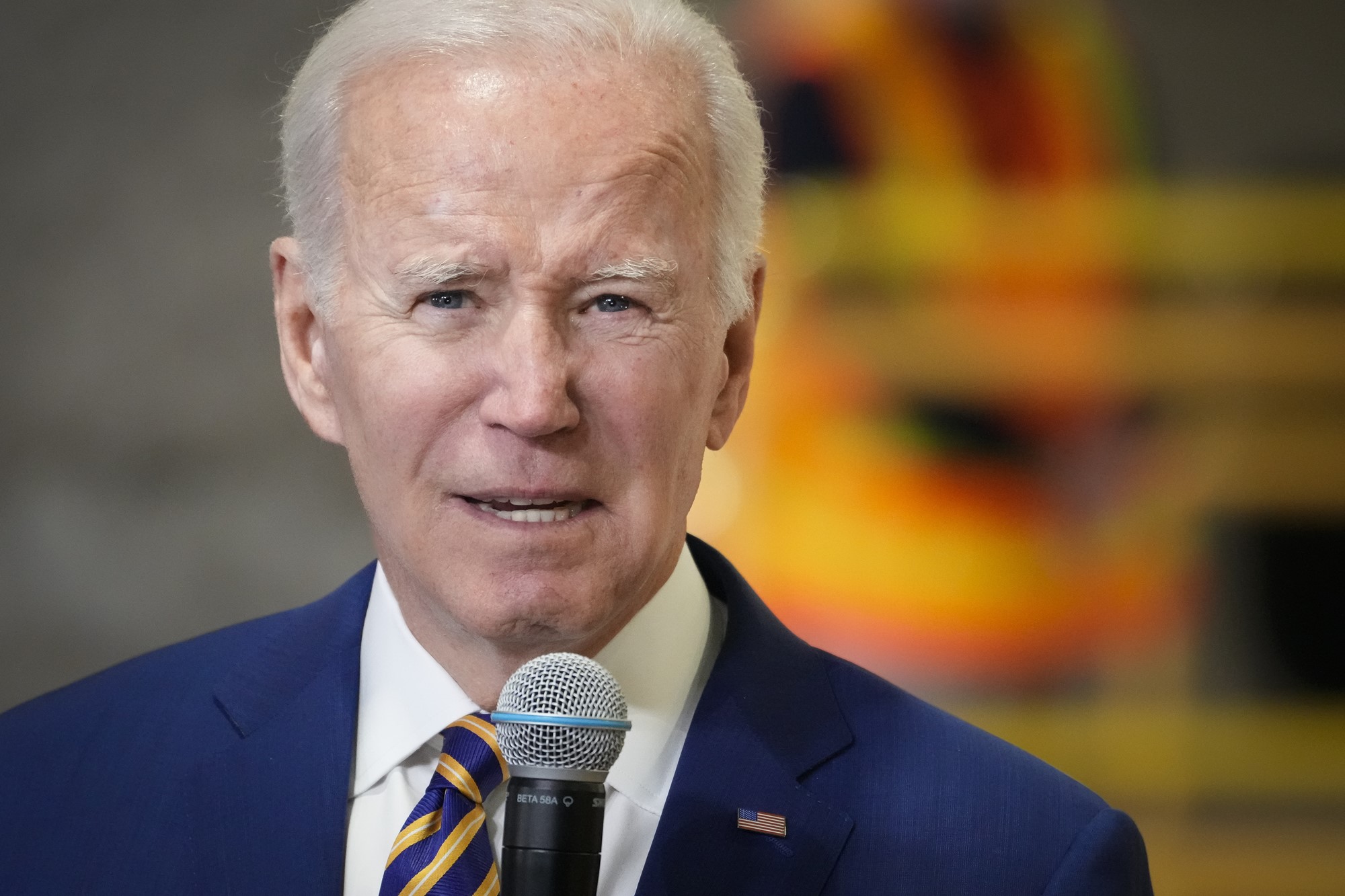 Joe Biden wears a blue suit and talks into a microphone.