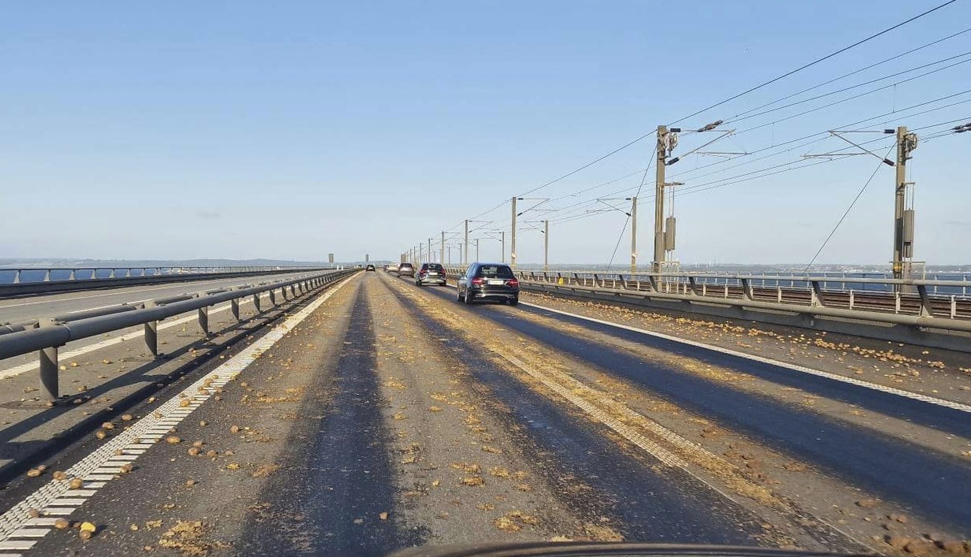 A wide road covered in potatoes, many squashed