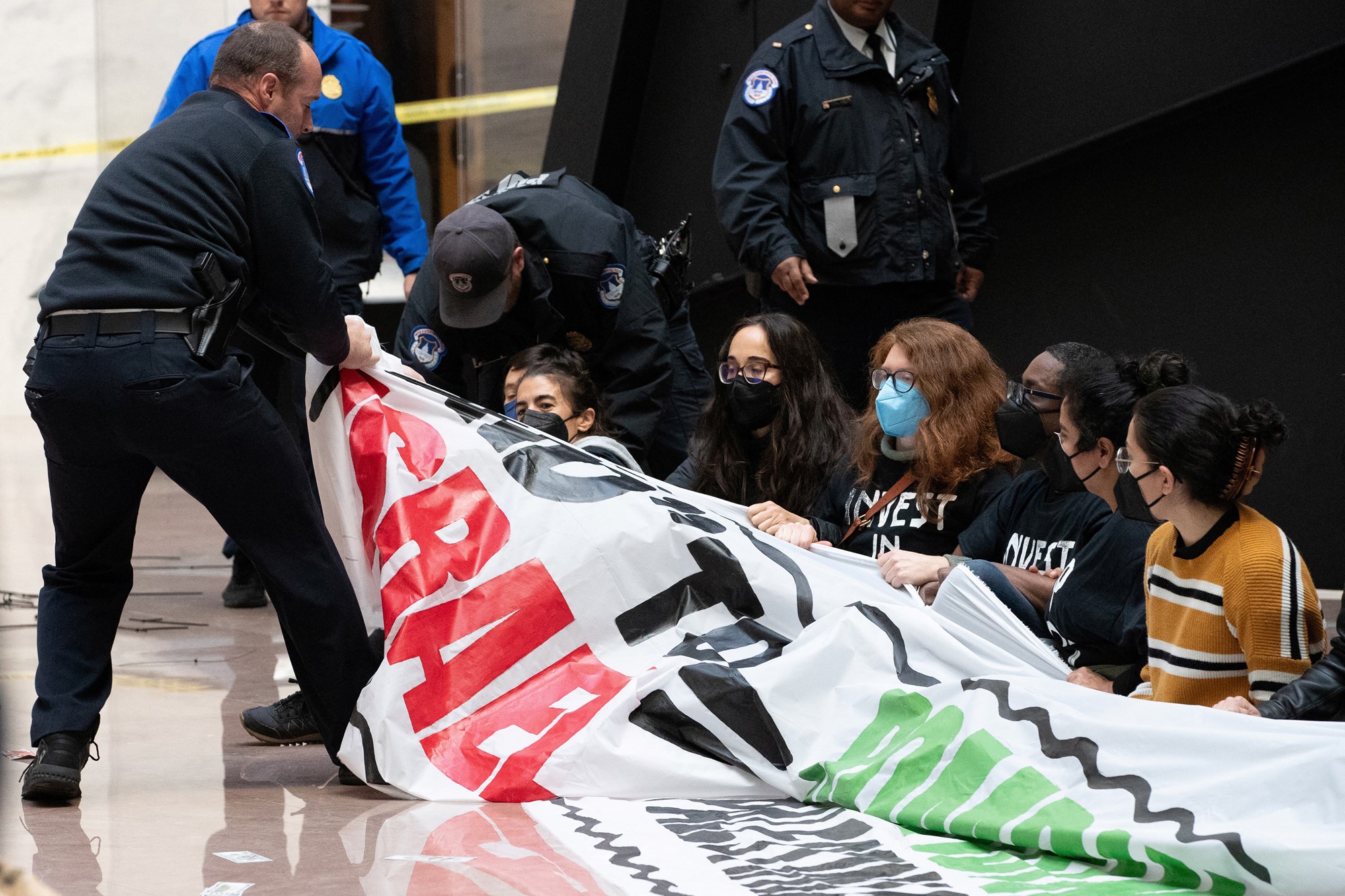 Police pull banner from activists sitting on the ground