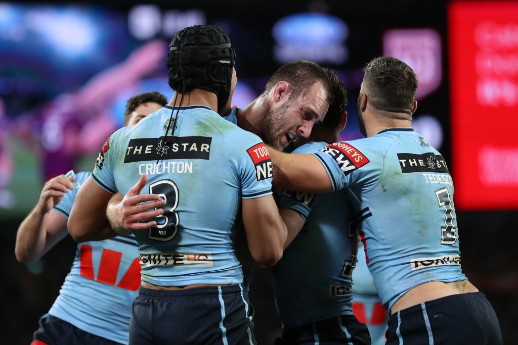Isaah Yeo is hugged by NSW Blues players.