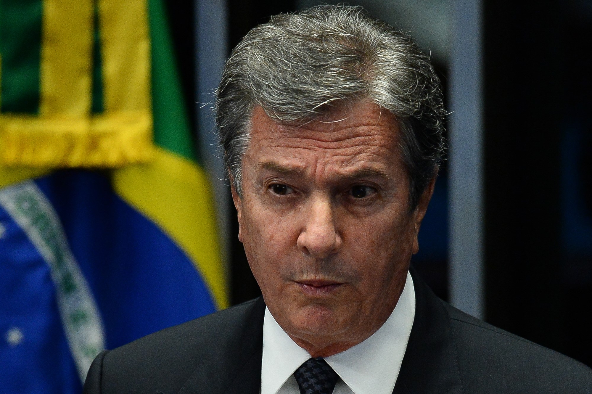 Fernando Collor de Mello speaks in front of a Brazilian flag