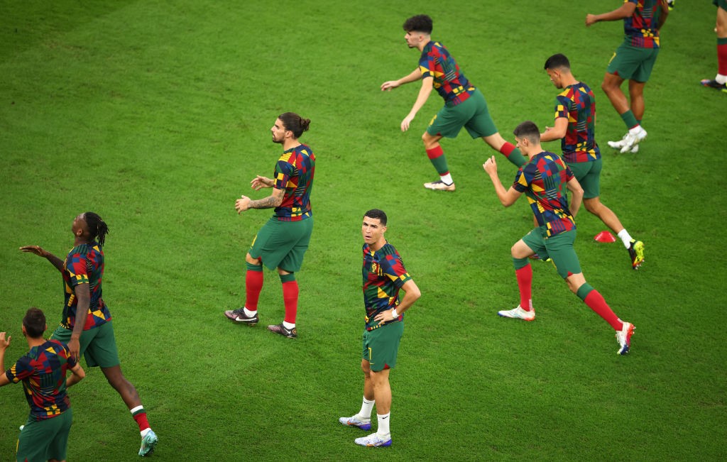 Cristiano Ronaldo stands with his hands on his hips while Portugal teammates warm up before their World Cup game against Switzerland.