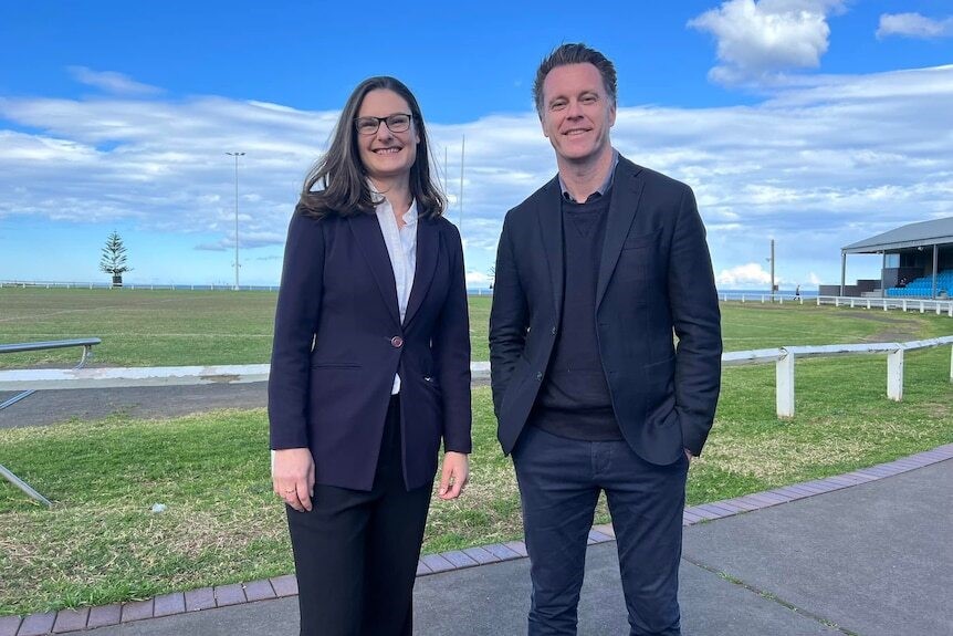  Man and woman in suits smiling outside,