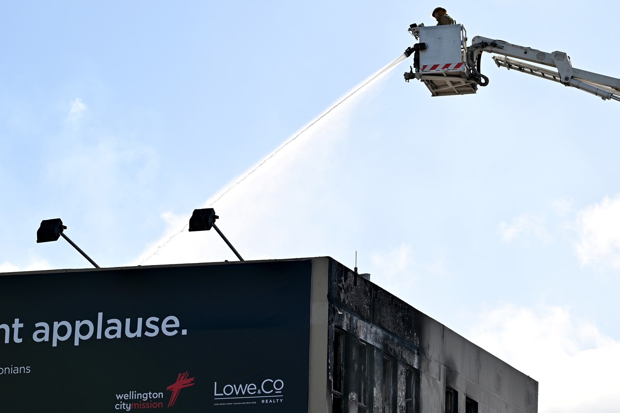 A firefighter in a cherry picker holds a hose.