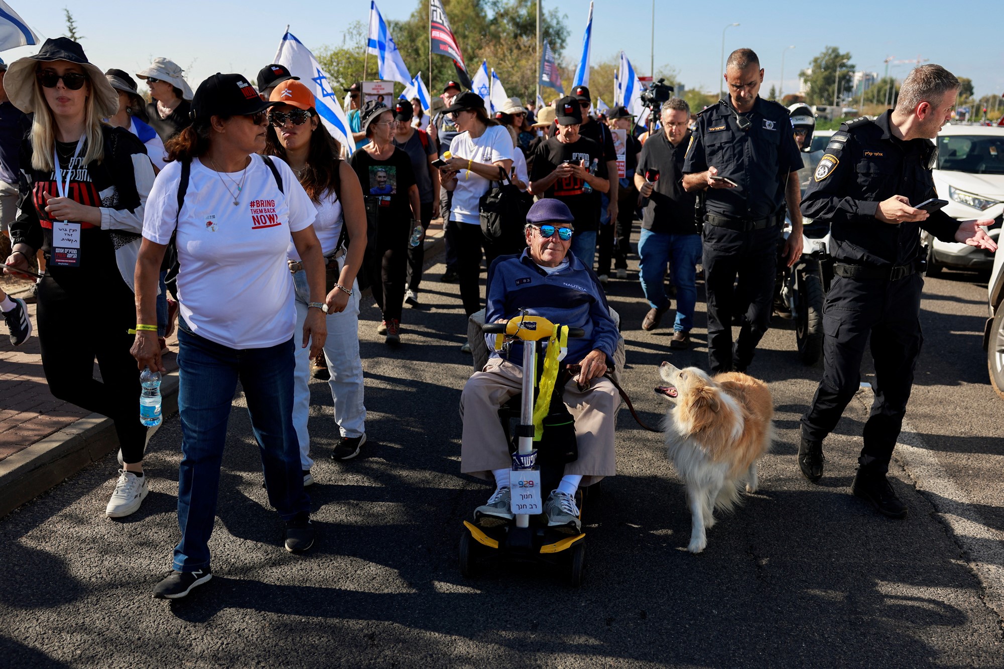 a group of people including a dog march with Israeli flags 