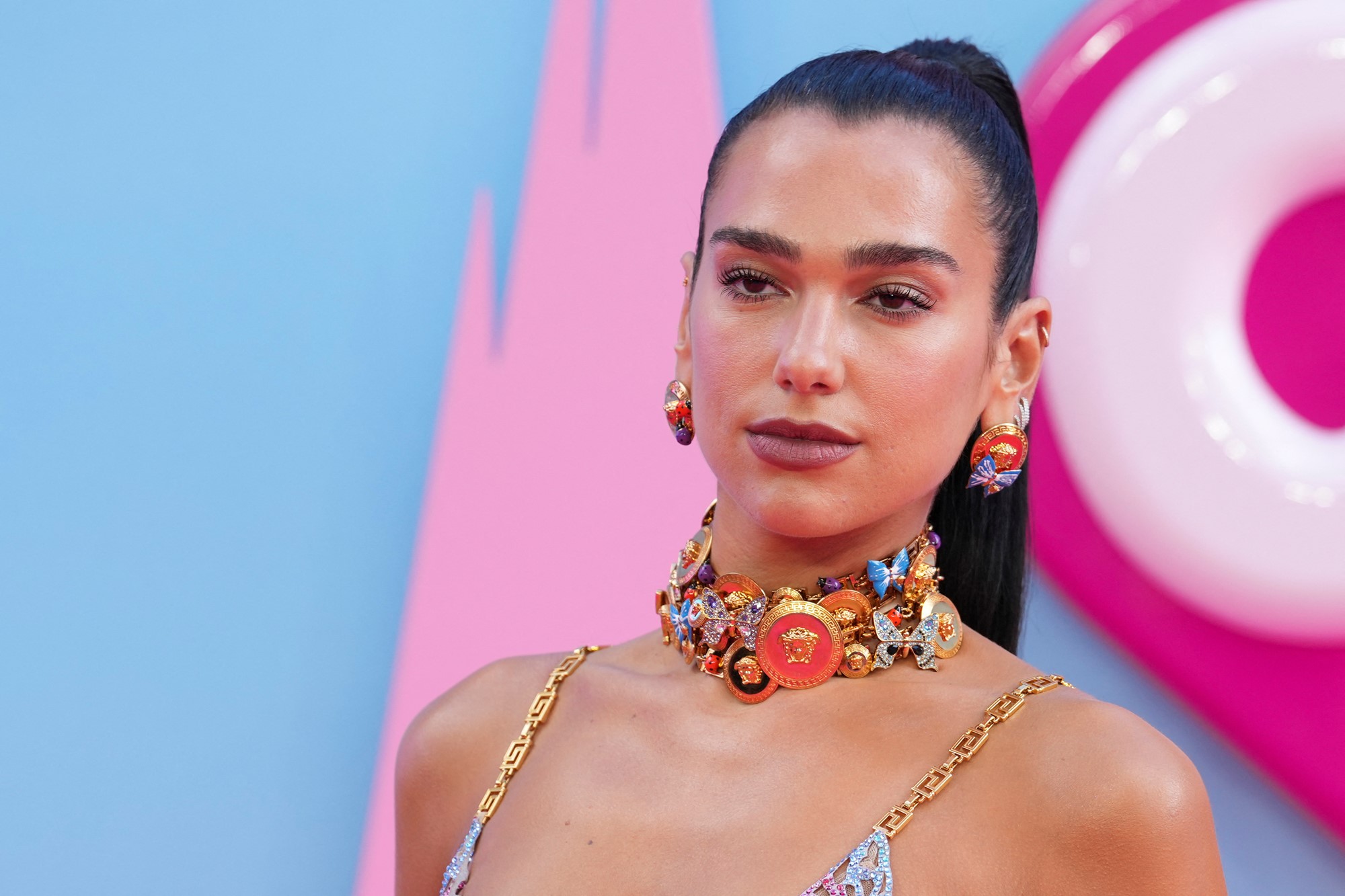 Dua Lipa with a slicked back updo, chunky necklace and earrings at barbie premiere