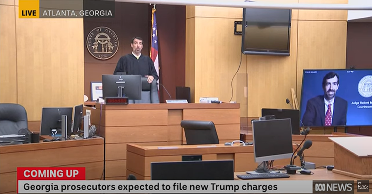 A judge standing and speaking in a courtroom