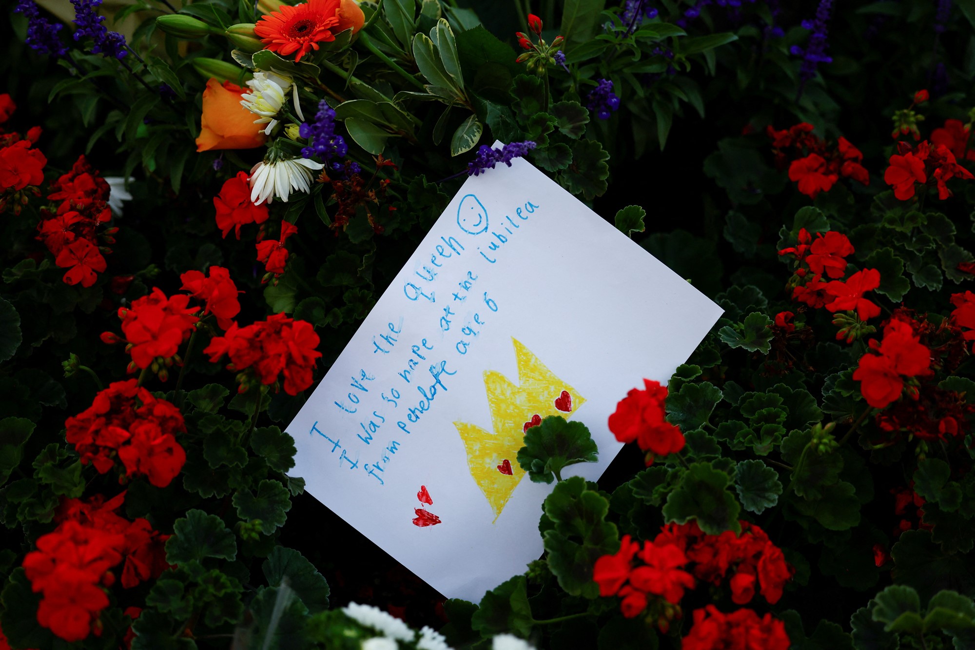 A card is seen amid floral tributes in a park near Buckingham Palace