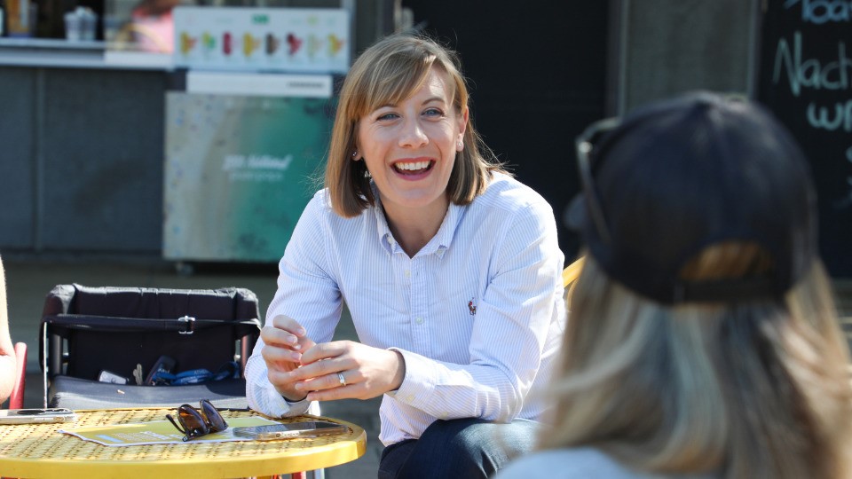 A woman in a white button up shirt smiles