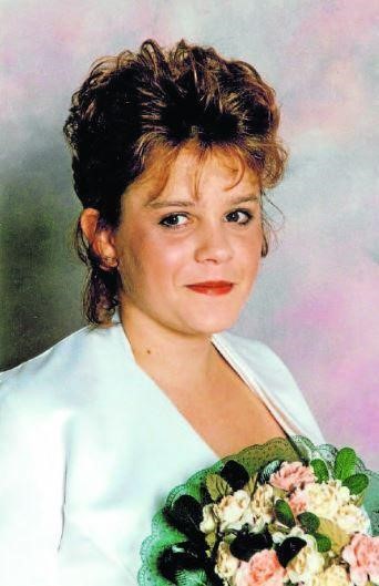 a woman in nineties style hair and clothes smiles at the camera