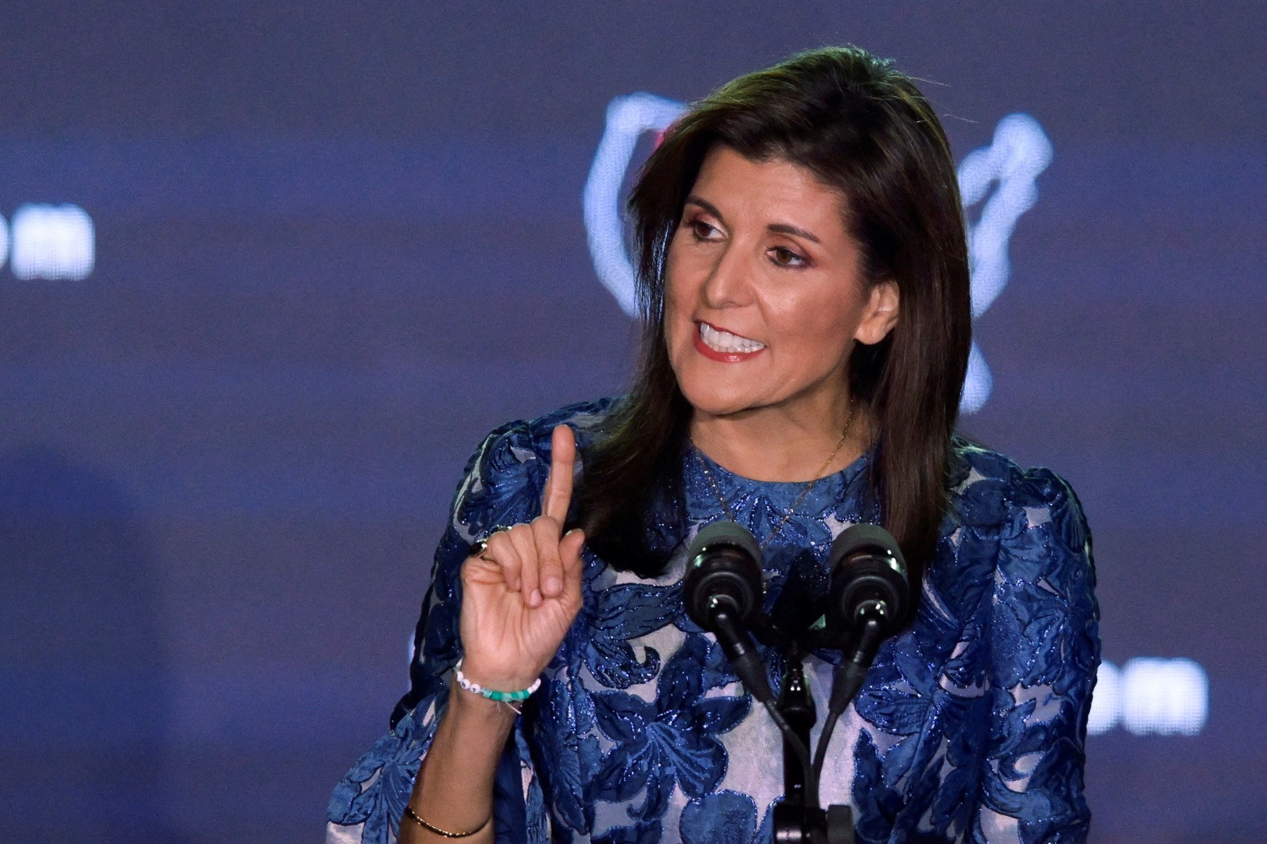 Nikki Haley speaks on stage and holds up her right index finger.