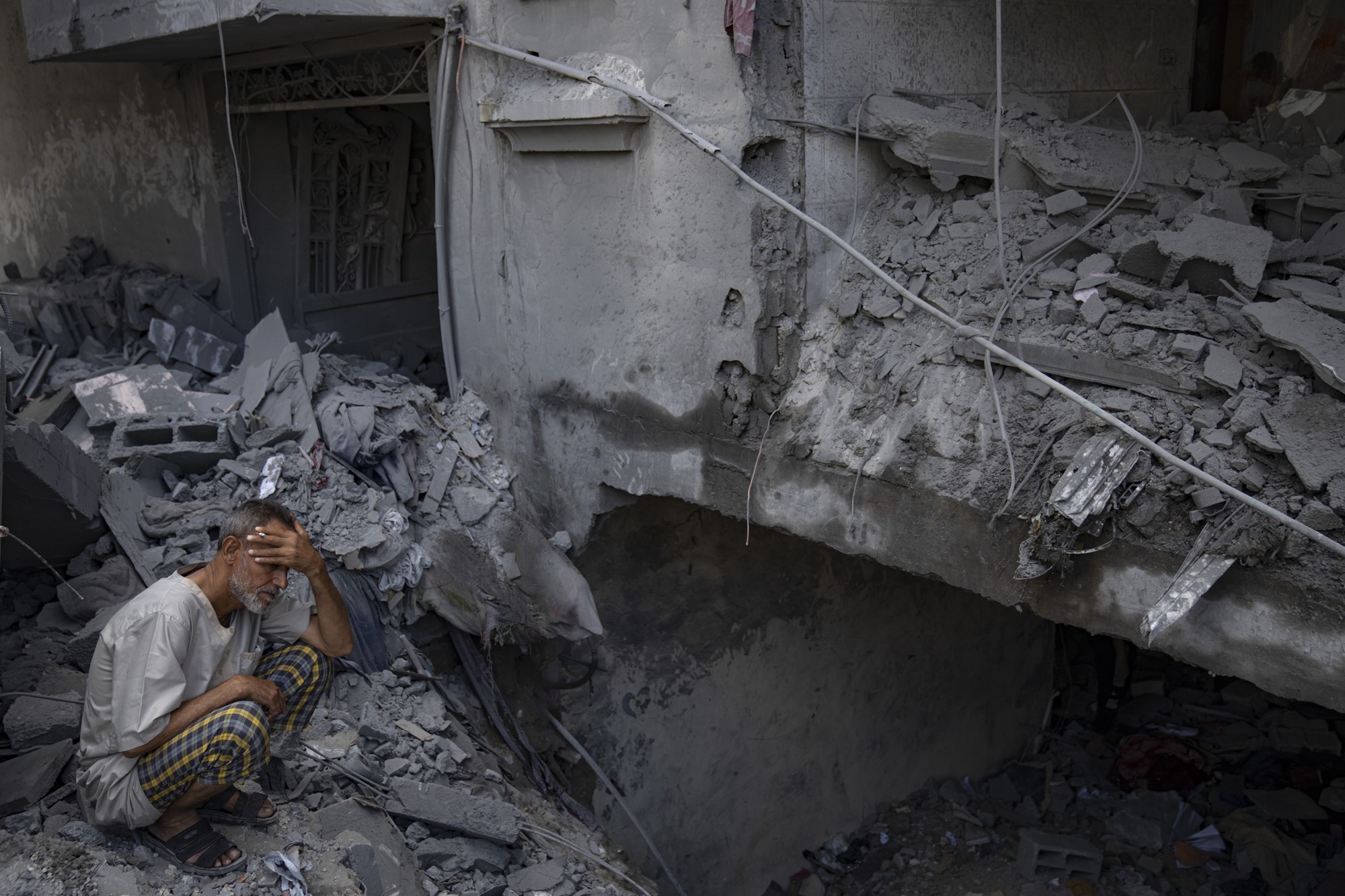 A man sits outside his building which was destroyed during Israeli bombardment