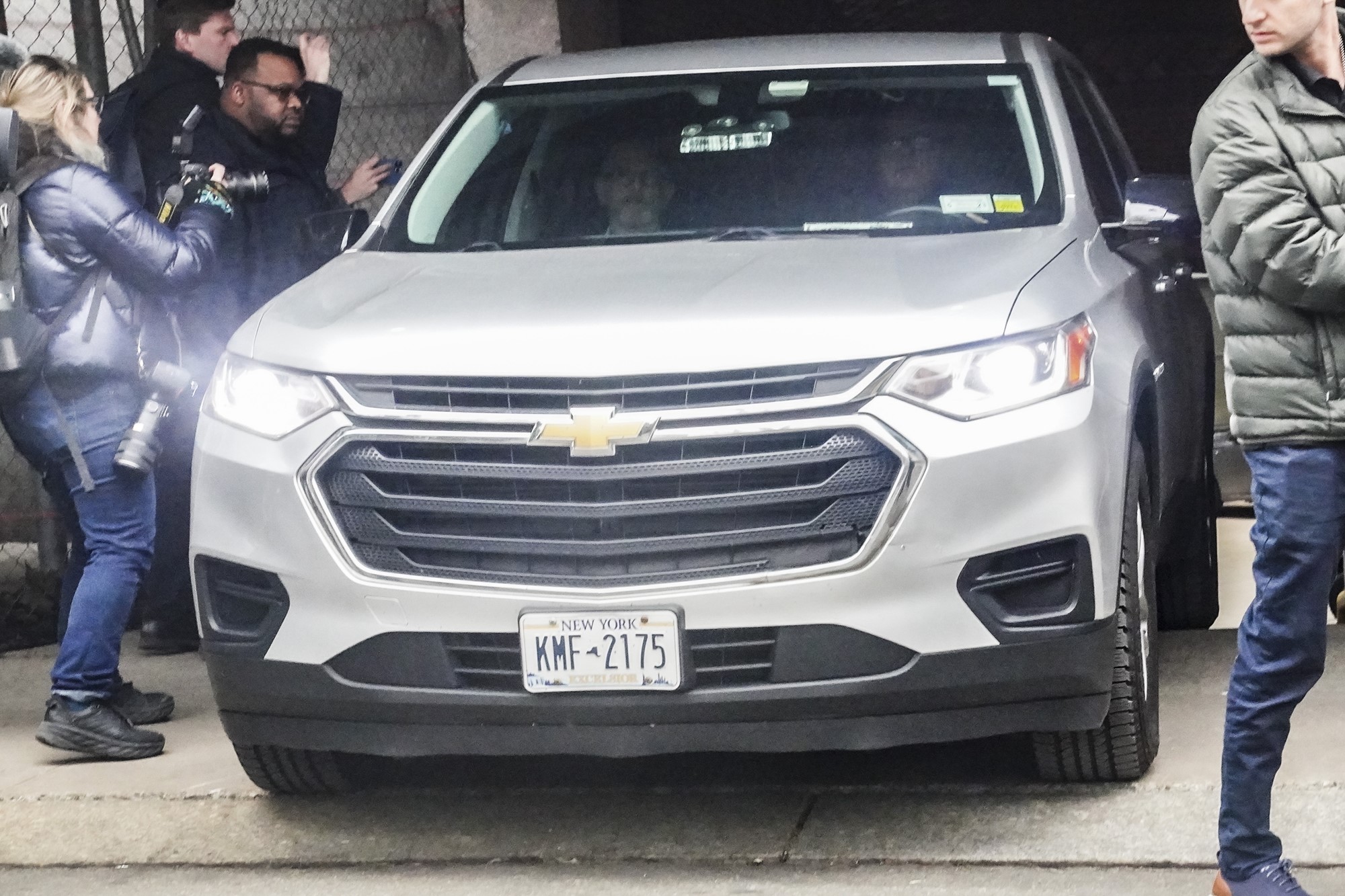 A car is surrounded by photographers. 