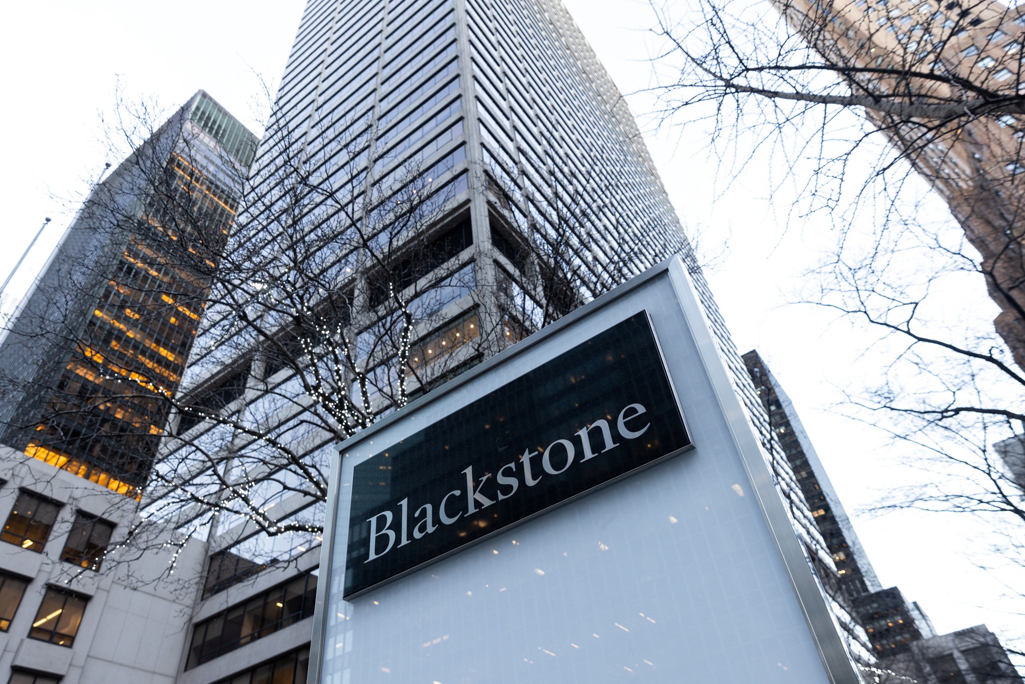 A skyscraper surrounded by other buildings with the word "Blackstone" on a sign.