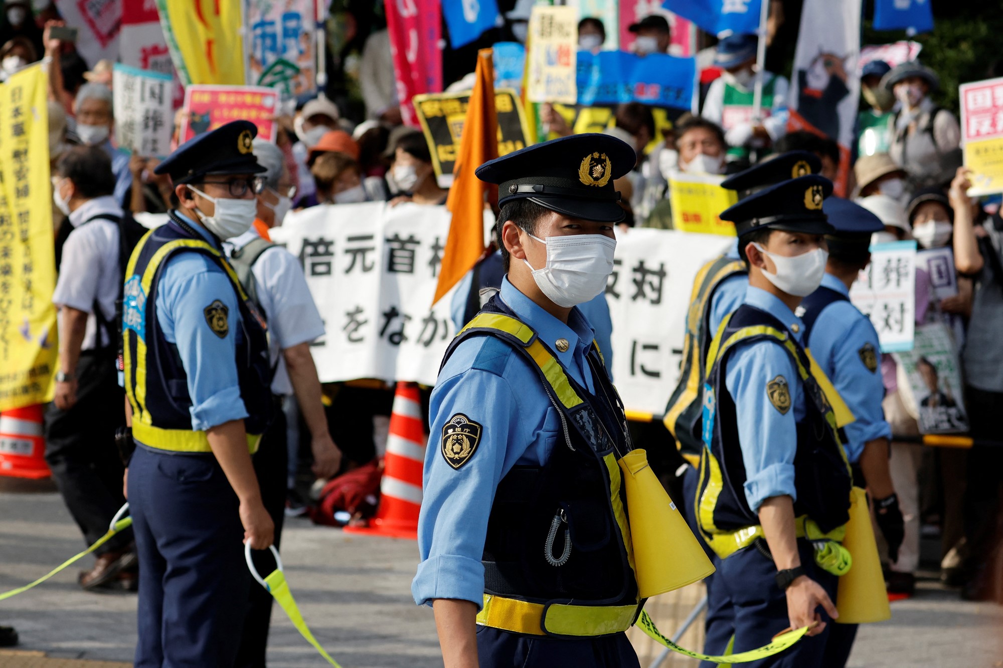 Police officers stand guard as protesters rally outside the parliament building against Japan's state funeral