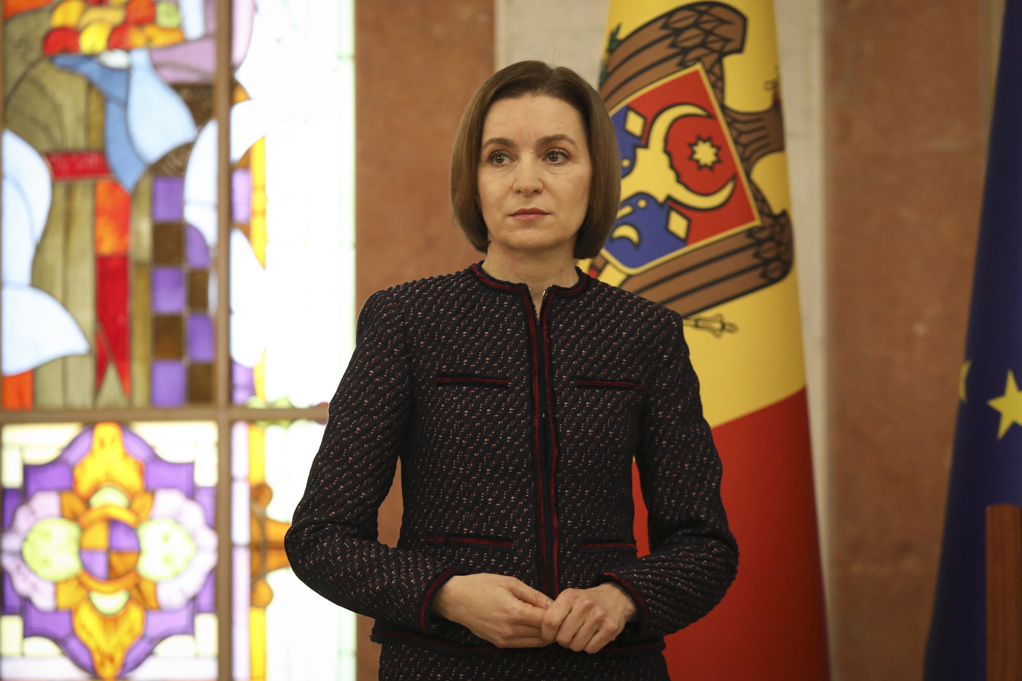 Maia stands in a chuch in front of a stained glass window and Moldovan flag.