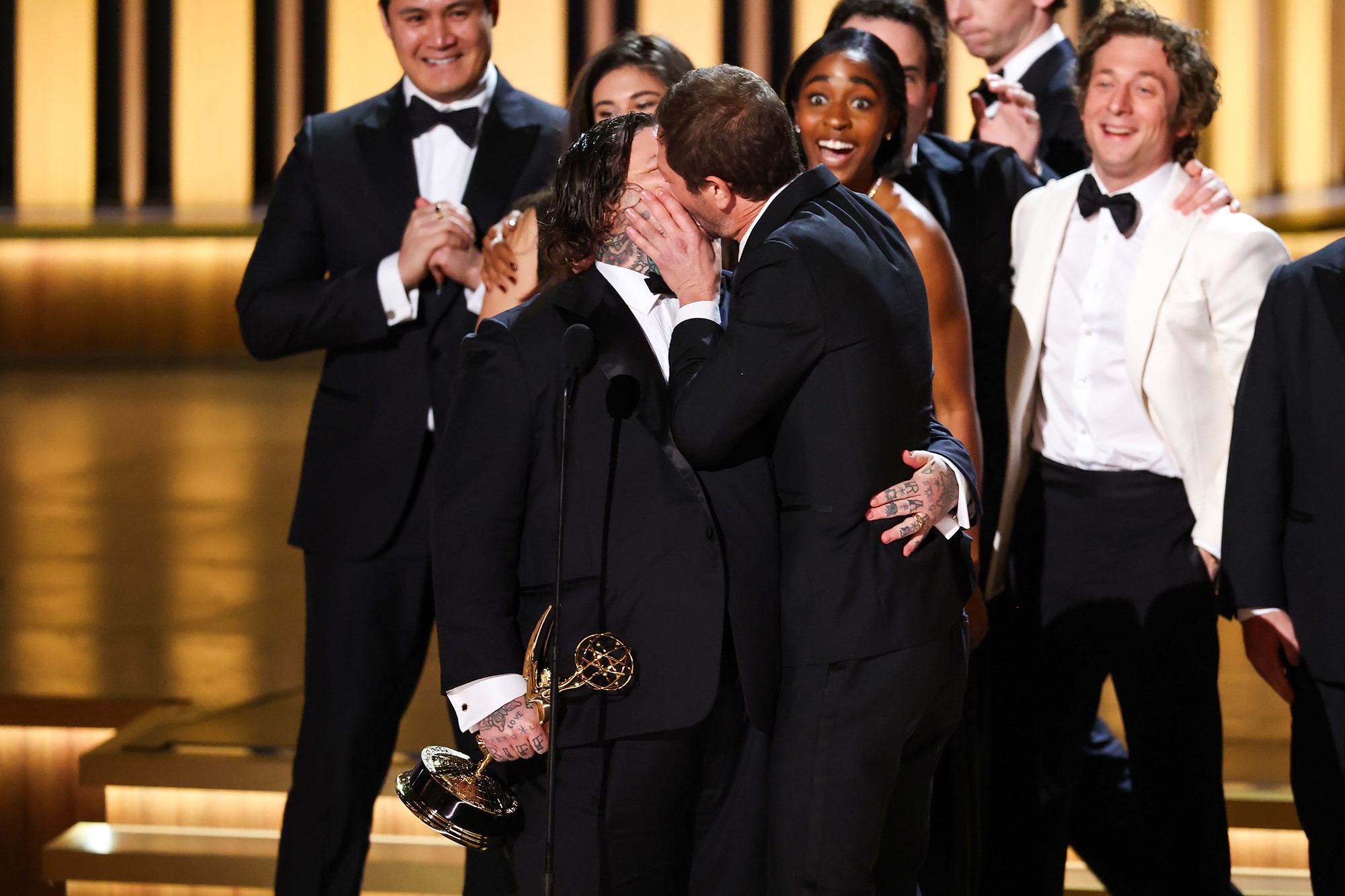 Two men in suits kissing.