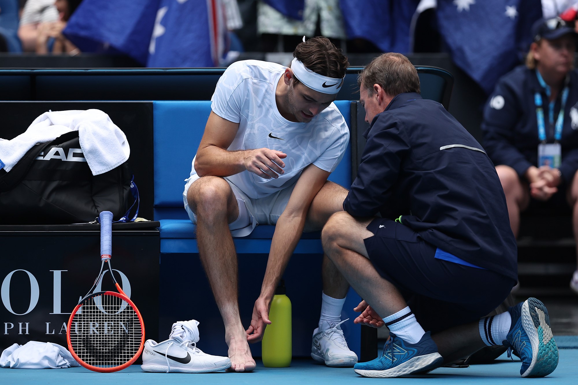 A tennis player and a phyios examine the payer's leg.