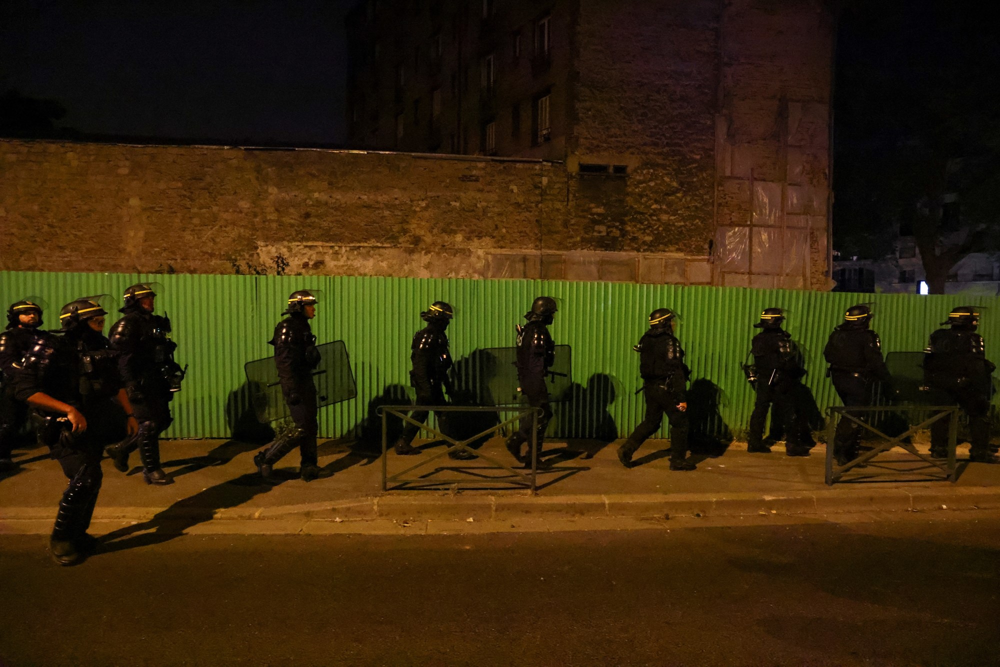 Police officers walkin riot gear down a street